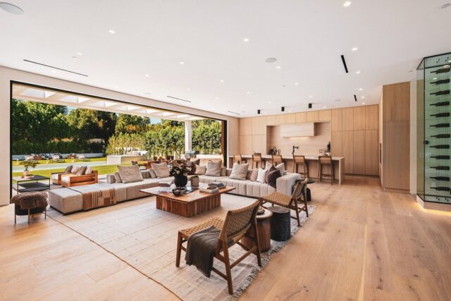 Spacious modern living room with open plan design, natural light, and view of lush garden through large sliding doors.