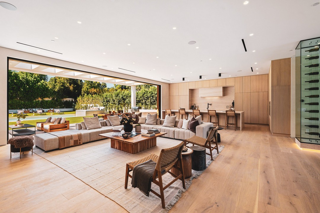 Spacious modern living room with open plan design, natural light, and view of lush garden through large sliding doors.